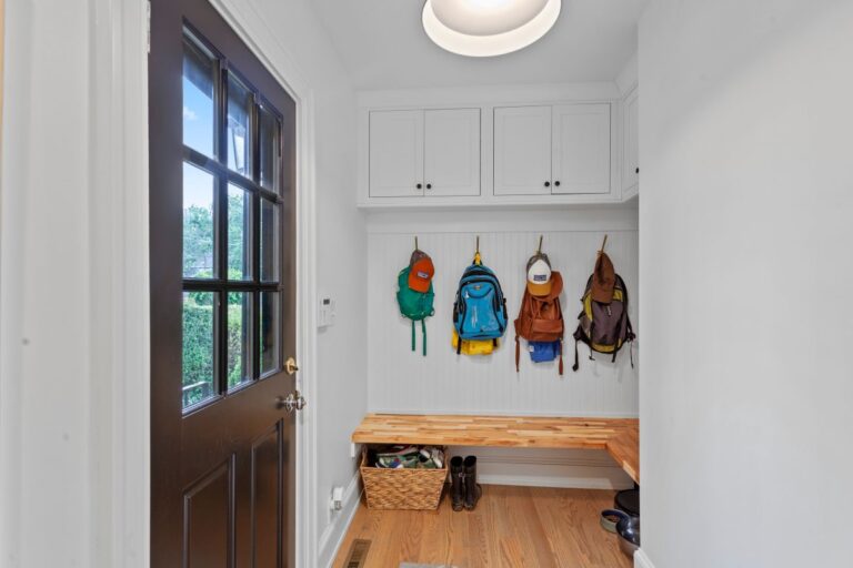 mudroom addition ideas family house backpacks hanging hooks white walls brown door